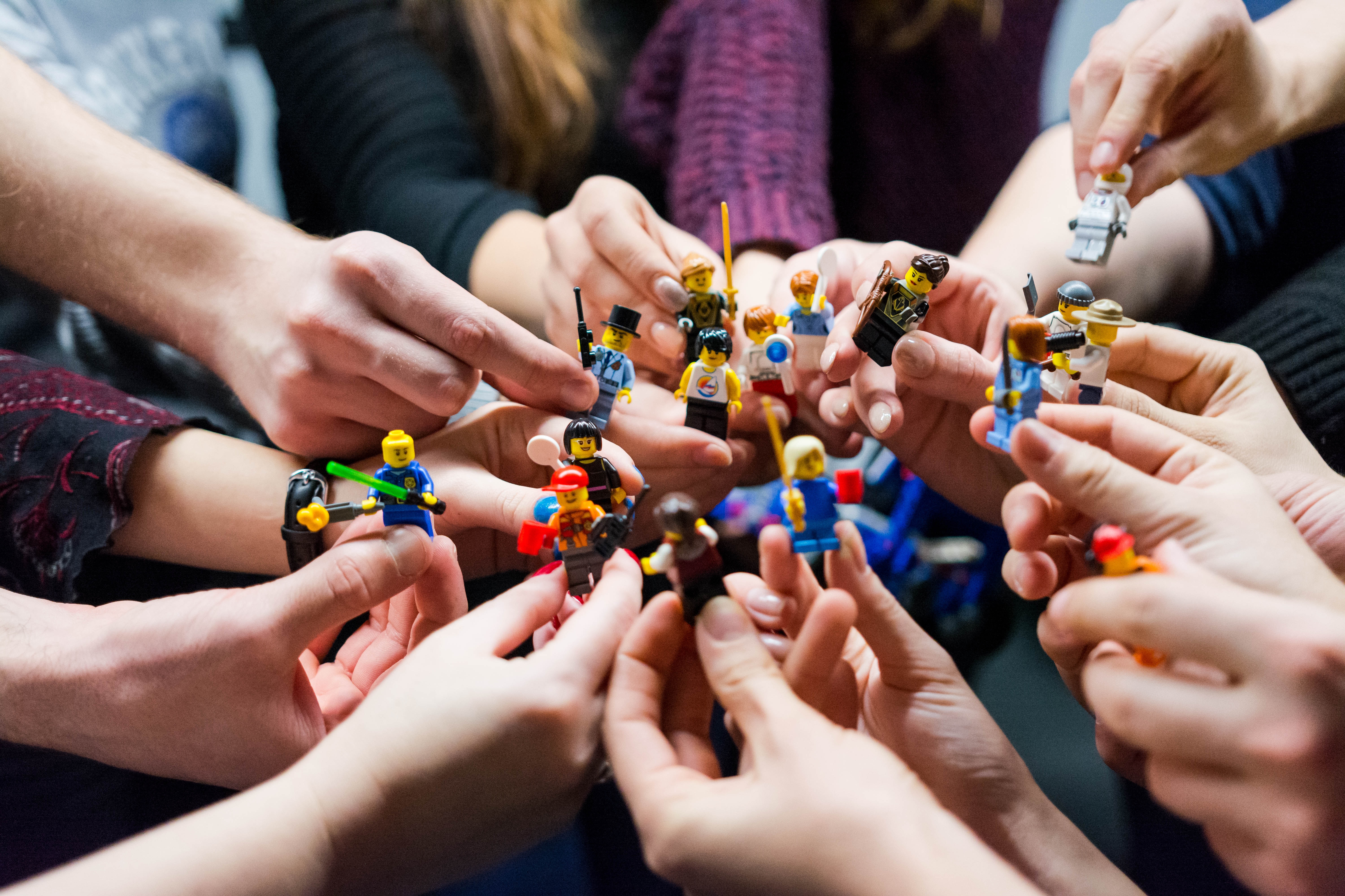 Hände halten Legofiguren in ihre Mitte